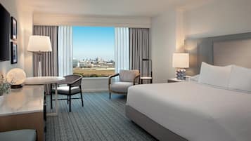 Habitación de hotel con cama, escritorio, silla, lámpara y vista a la ciudad.
