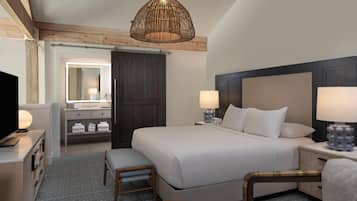 A hotel room with a bed, bedside lamps, a television, a mirror, and a wardrobe.