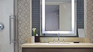 Un baño moderno con un espejo grande, un lavamanos y un perchero para toallas.