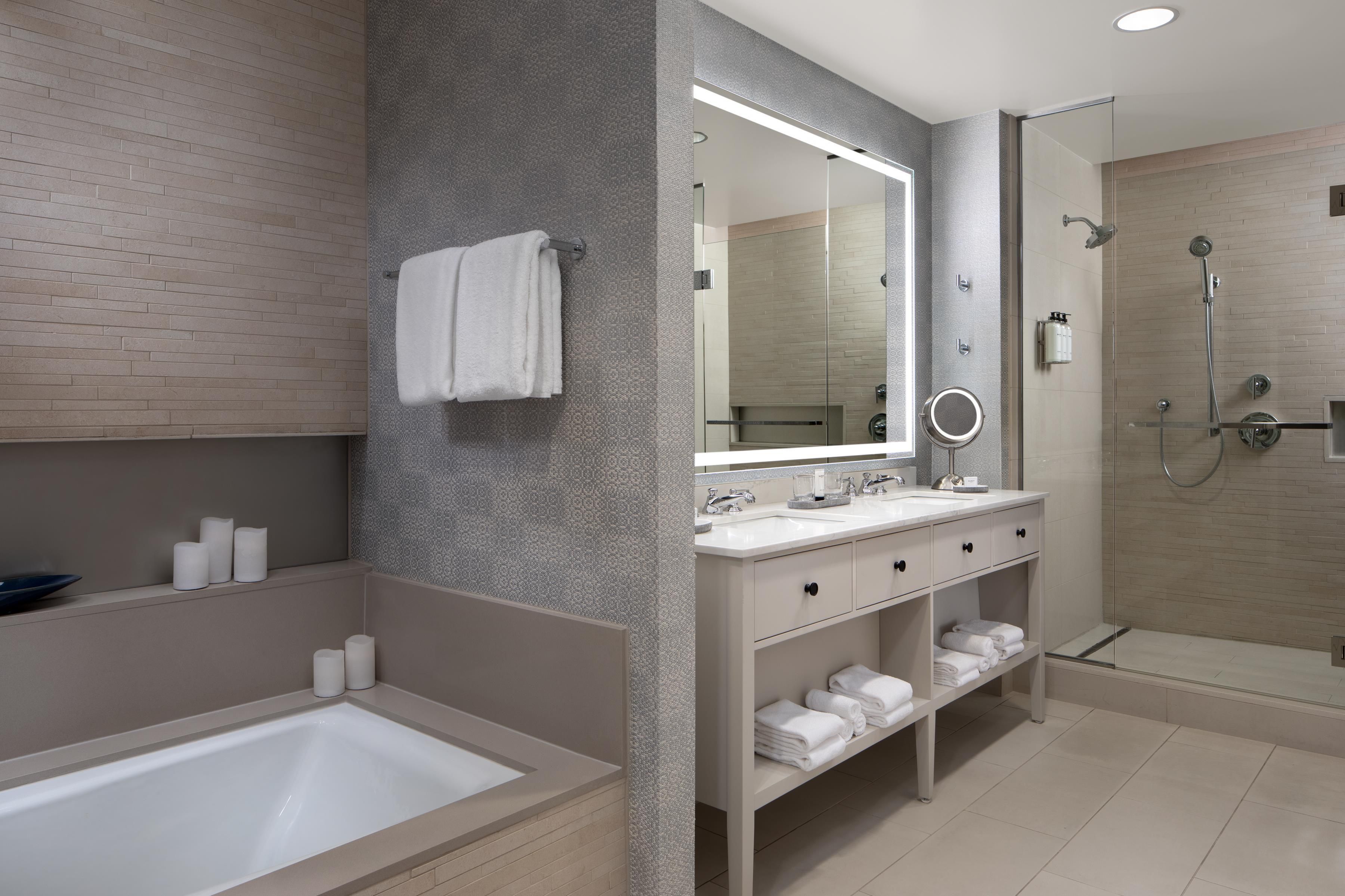 A modern bathroom with a bathtub, a vanity with a mirror, and a shower area.