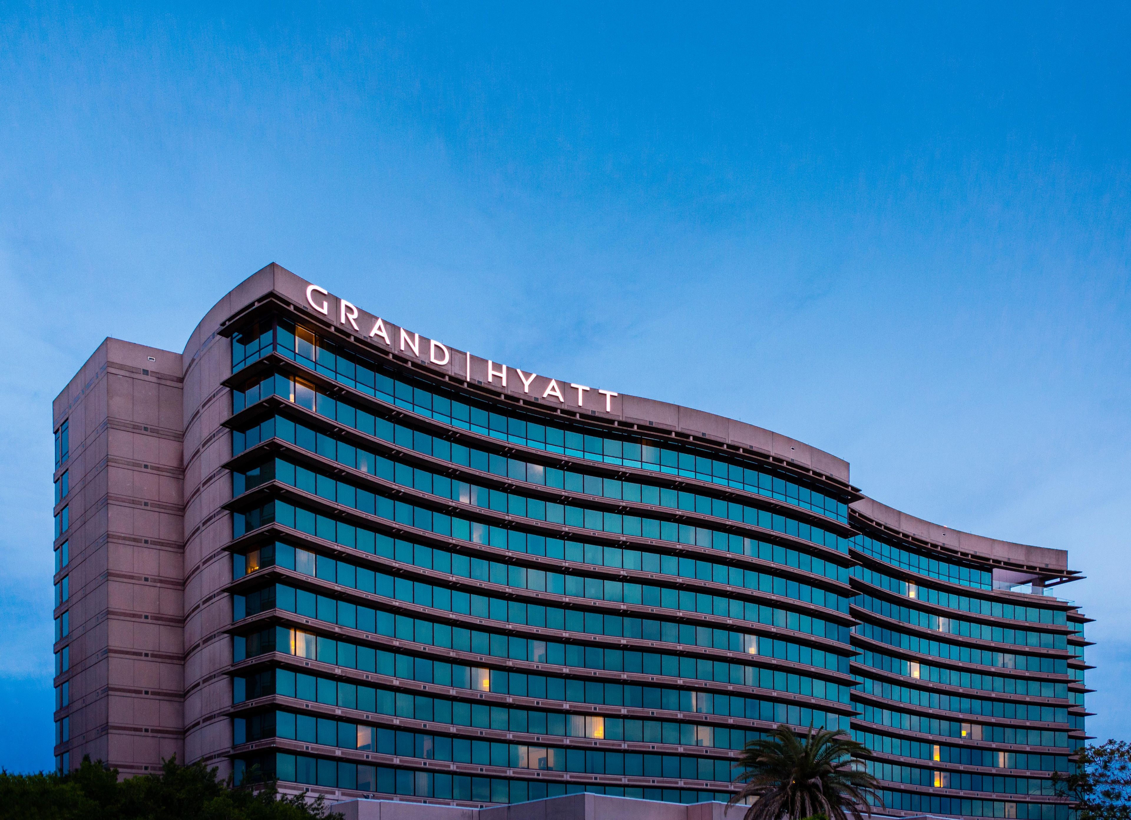 Un hotel de varios pisos con fachada curva y un llamativo letrero 'GRAND HYATT'.