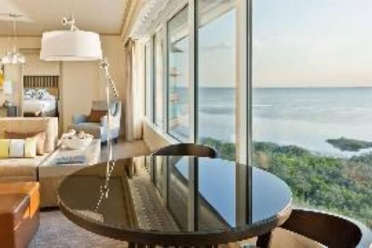 Moderni hotellihuone, jossa on suuri ikkuna, pyöreä pöytä ja sohva.