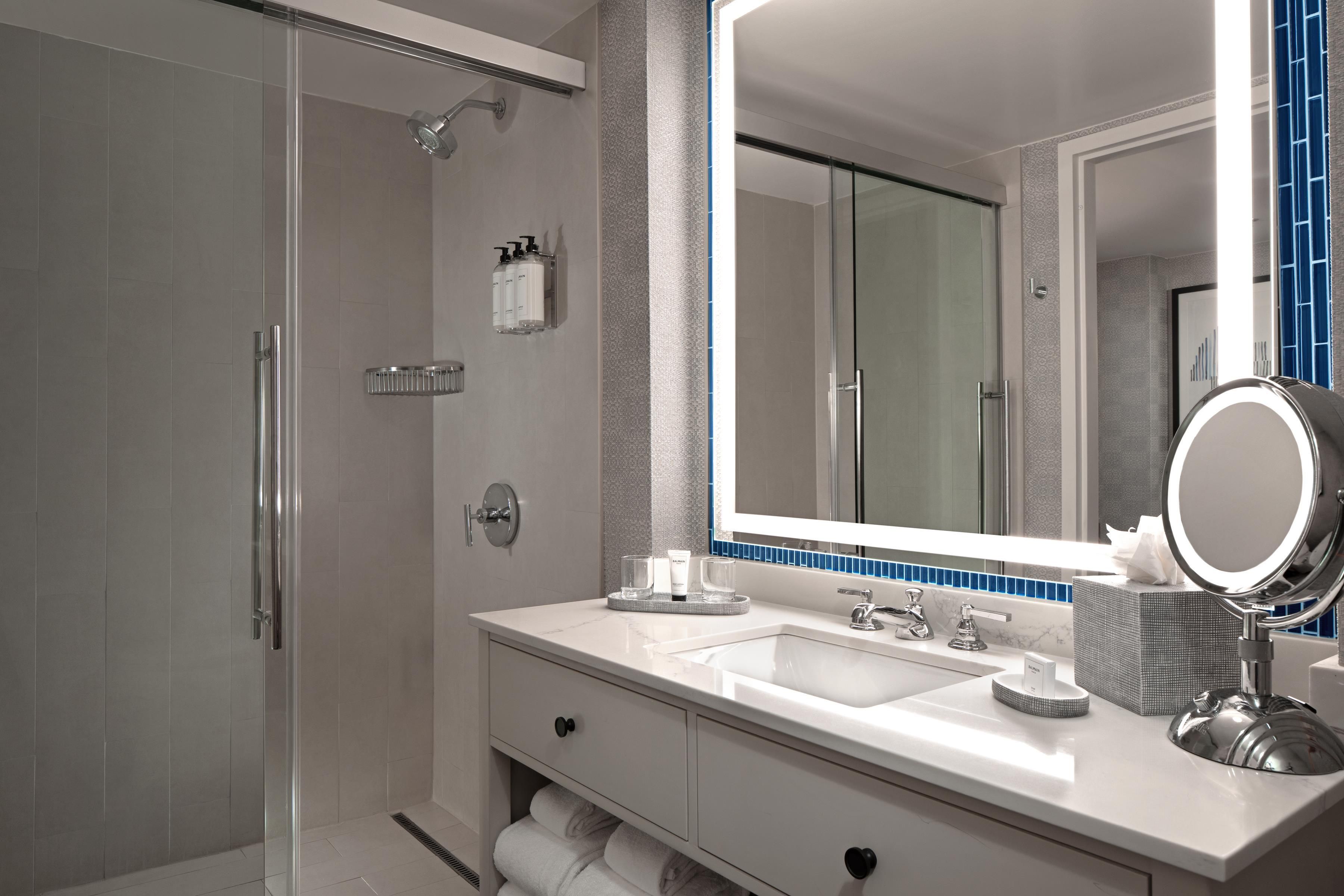 Un baño moderno con cabina de ducha, un espejo grande y tocador con lavabo.