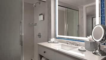 Un baño moderno con cabina de ducha, un espejo grande y tocador con lavabo.