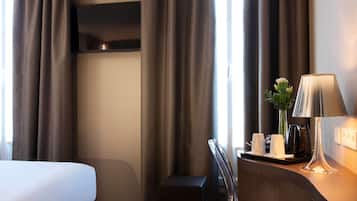 Una habitación de hotel con una cama, un escritorio, una lámpara y un florero con flores.