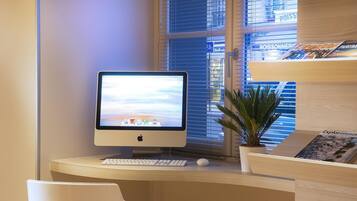 A modern office desk with an Apple iMac, a keyboard, a mouse, and a potted plant.