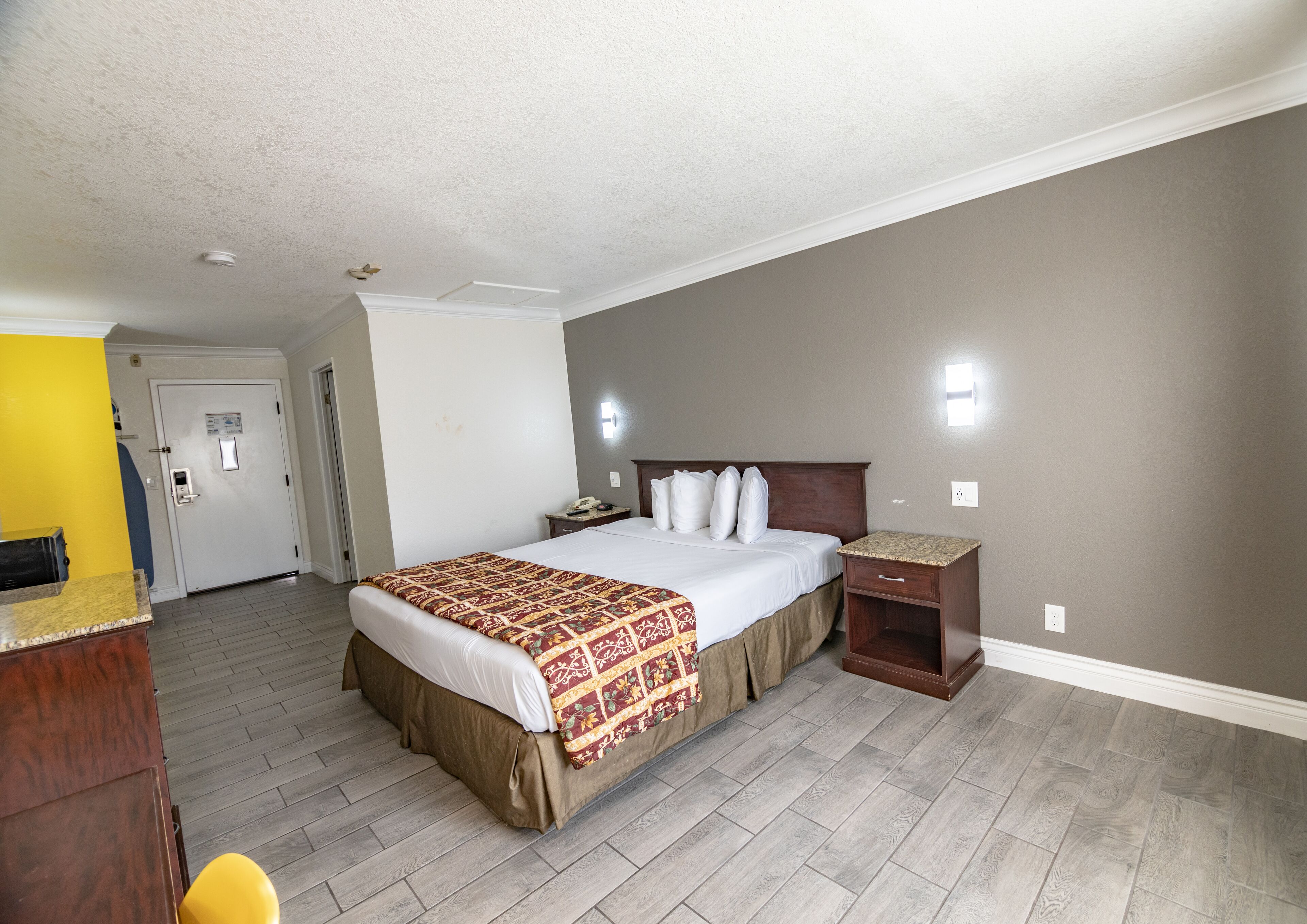 Une chambre d’hôtel avec un grand lit, une table de chevet, une commode, un bureau et une chaise.