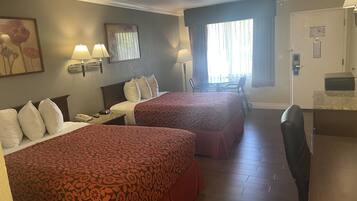 A hotel room with two beds, a desk, a chair, a window with curtains, and a door with a lock.