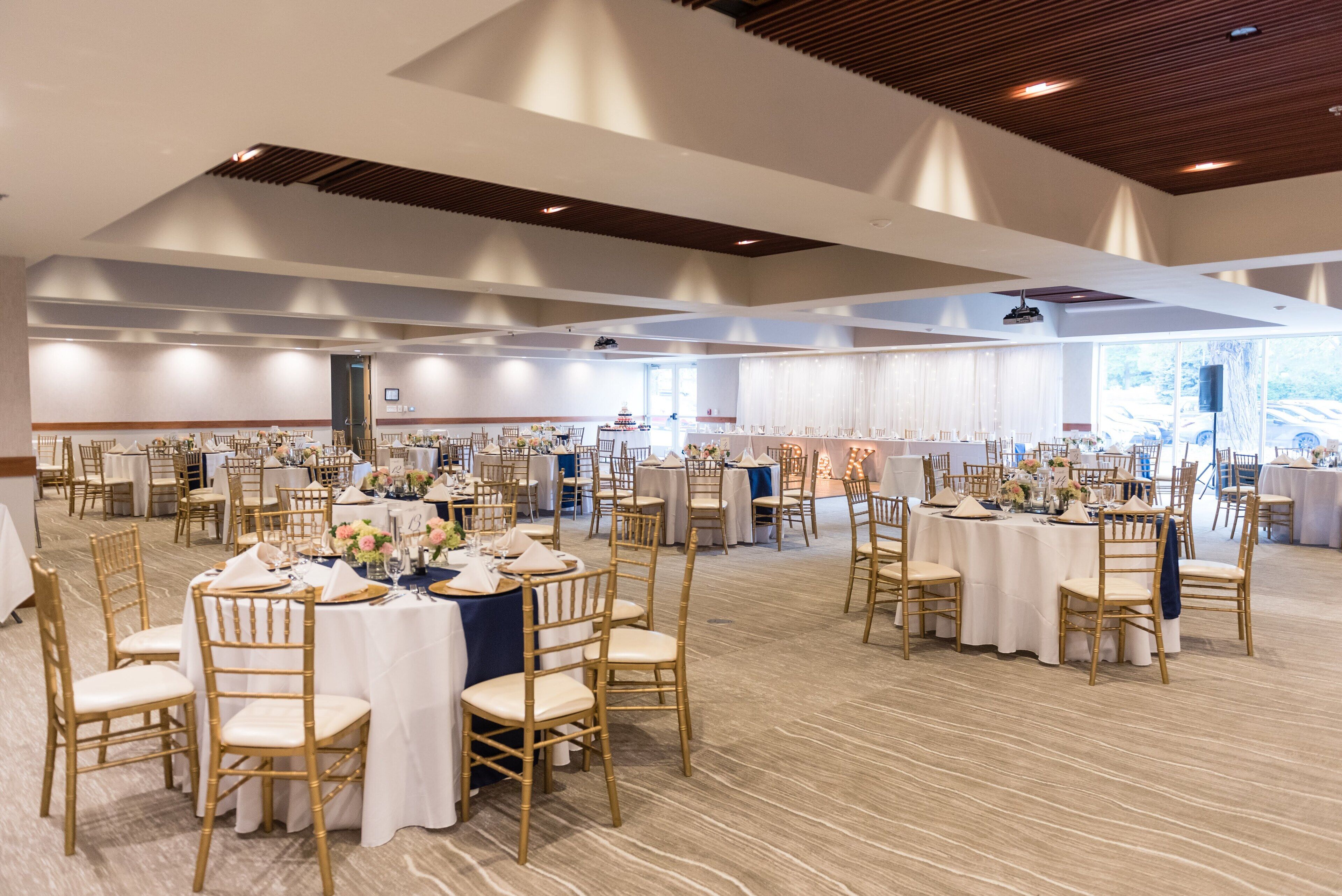 A spacious banquet hall with multiple round tables and chairs, arranged for a formal event.