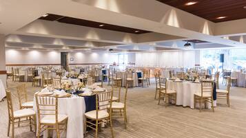 A spacious banquet hall with multiple round tables and chairs, arranged for a formal event.