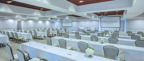 A conference room with rows of tables and chairs, white tablecloths, and a wooden ceiling.