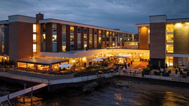 A hotel with outdoor dining and a river view. - Delamar Traverse City (Traverse City)
