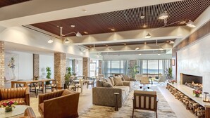A spacious living area with leather sofas, a fireplace, and a large window overlooking the city. - Delamar Traverse City (Traverse City)