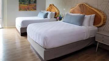 A modern bedroom with two beds, a wooden headboard, a geometric wall pattern, and a wooden floor.