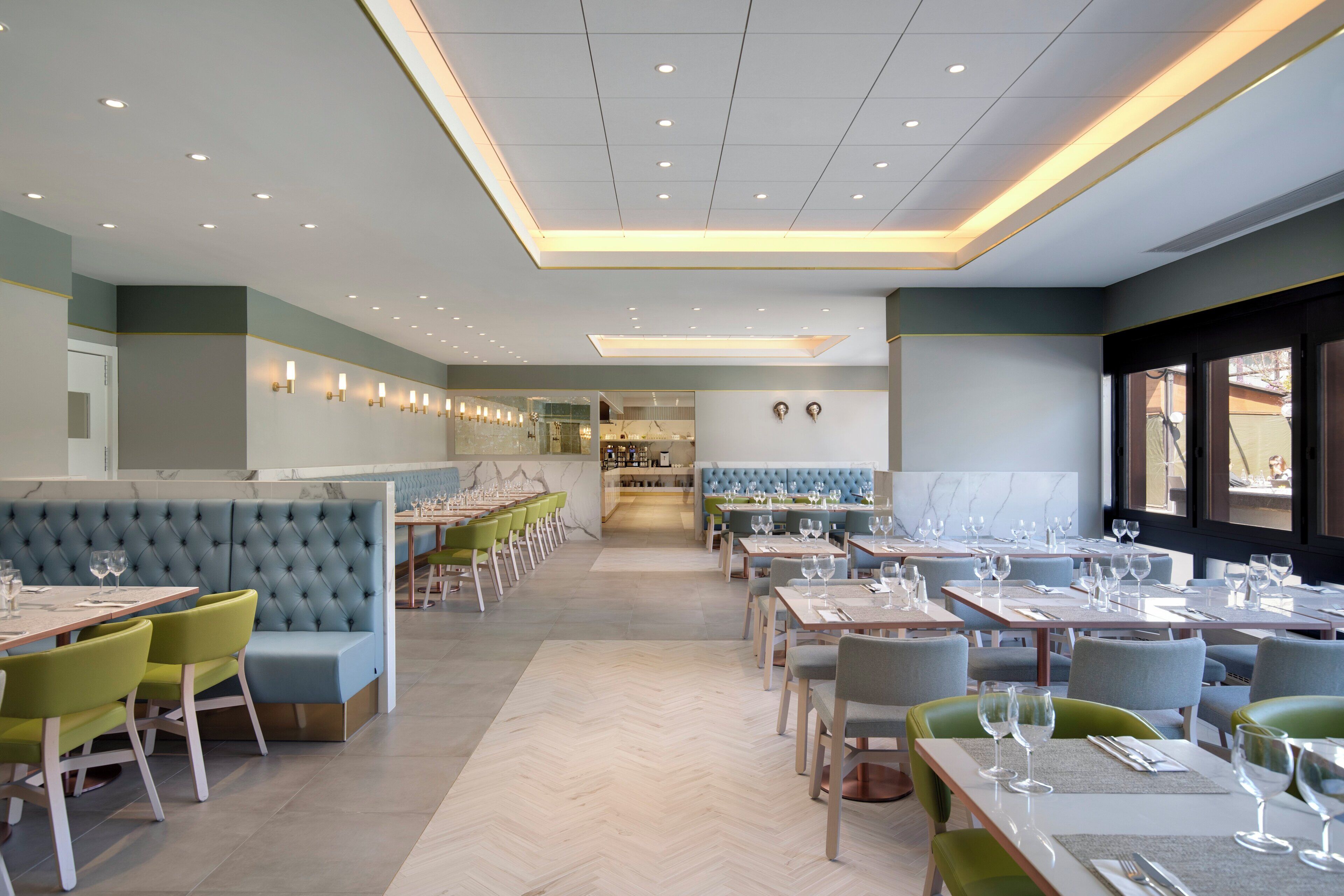 L’intérieur d’un restaurant, avec des banquettes, des tables et un coin bar.