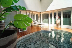 A modern indoor pool area with a wooden floor, a large potted monstera plant, and a lounge chair. - Crowne Plaza Zürich by IHG (Zürich)