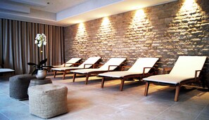 A spa area with stone walls, wooden lounge chairs, and a vase with flowers. - Crowne Plaza Zürich by IHG (Zürich)