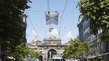 A tram moving through a busy urban street with pedestrians and buildings.