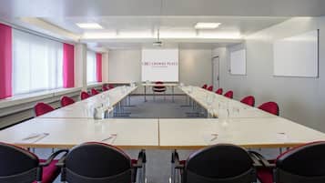A conference room with a long table, red chairs, a projector screen, and a whiteboard.