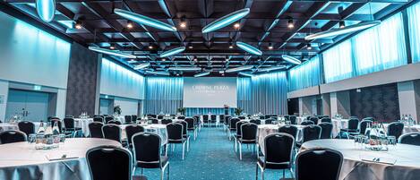 A conference room with tables and chairs, a projector screen, and a blue carpet.