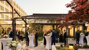 An outdoor event with round tables, guests, and a garden setting. - Crowne Plaza Zürich by IHG (Zürich)