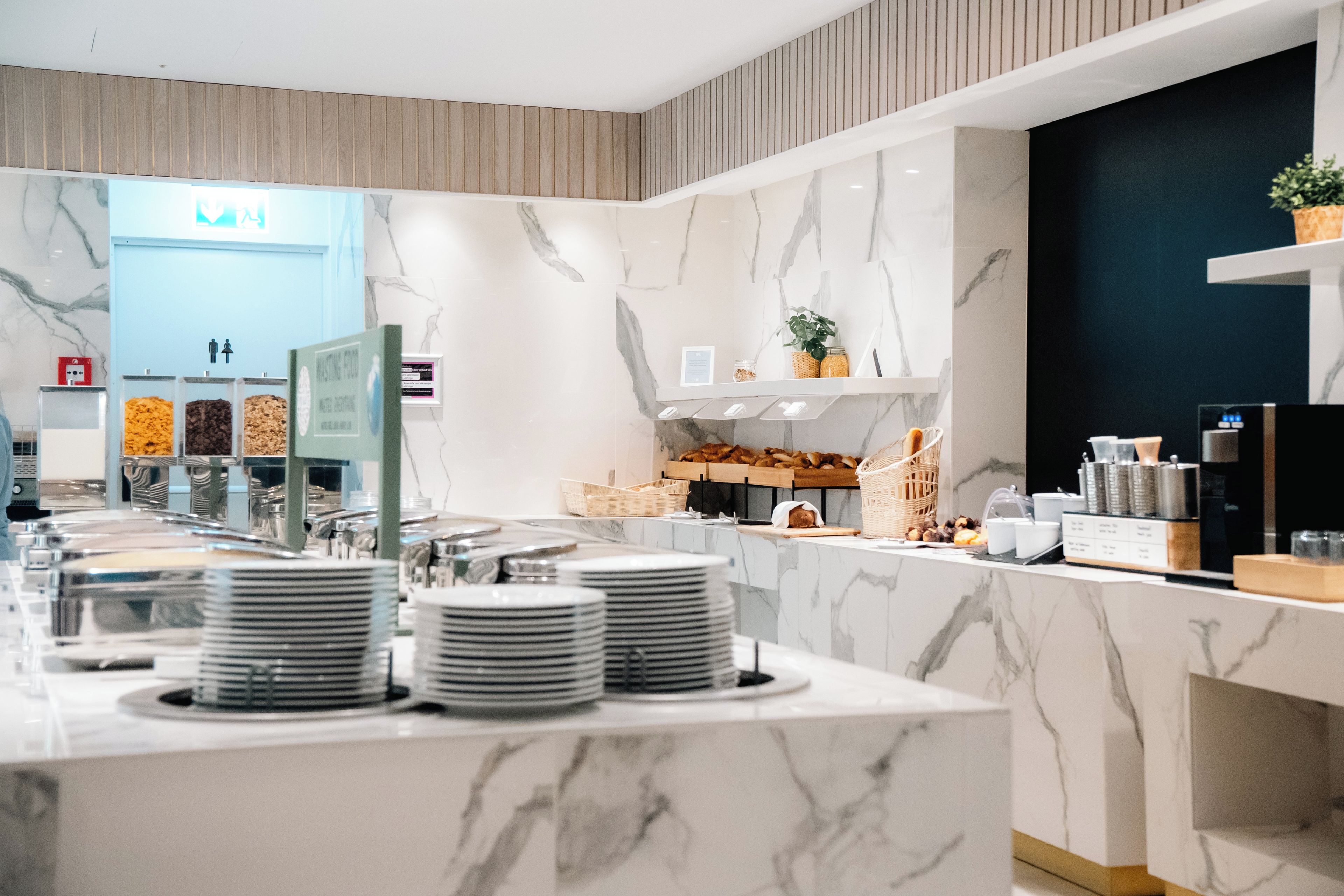 A buffet setup with marble countertops, stacked plates, and various food items.