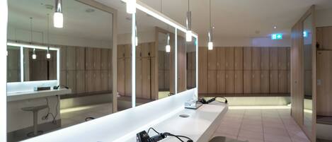 A modern bathroom with a long counter, a large mirror, and wooden cabinets.