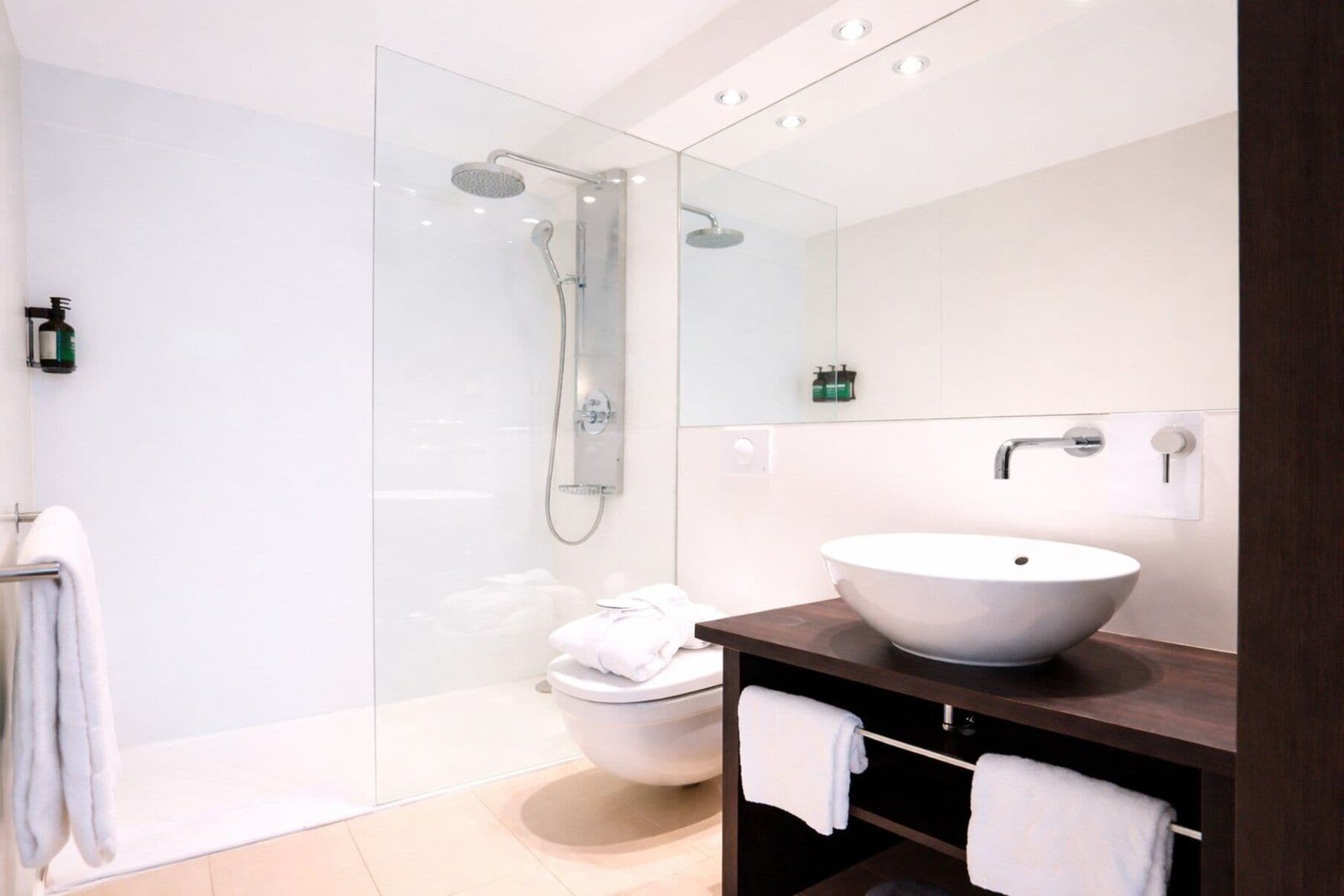 Une salle de bain moderne avec une douche à parois de verre, un lavabo blanc et des toilettes.