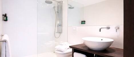 Une salle de bain moderne avec une douche à parois de verre, un lavabo blanc et des toilettes.