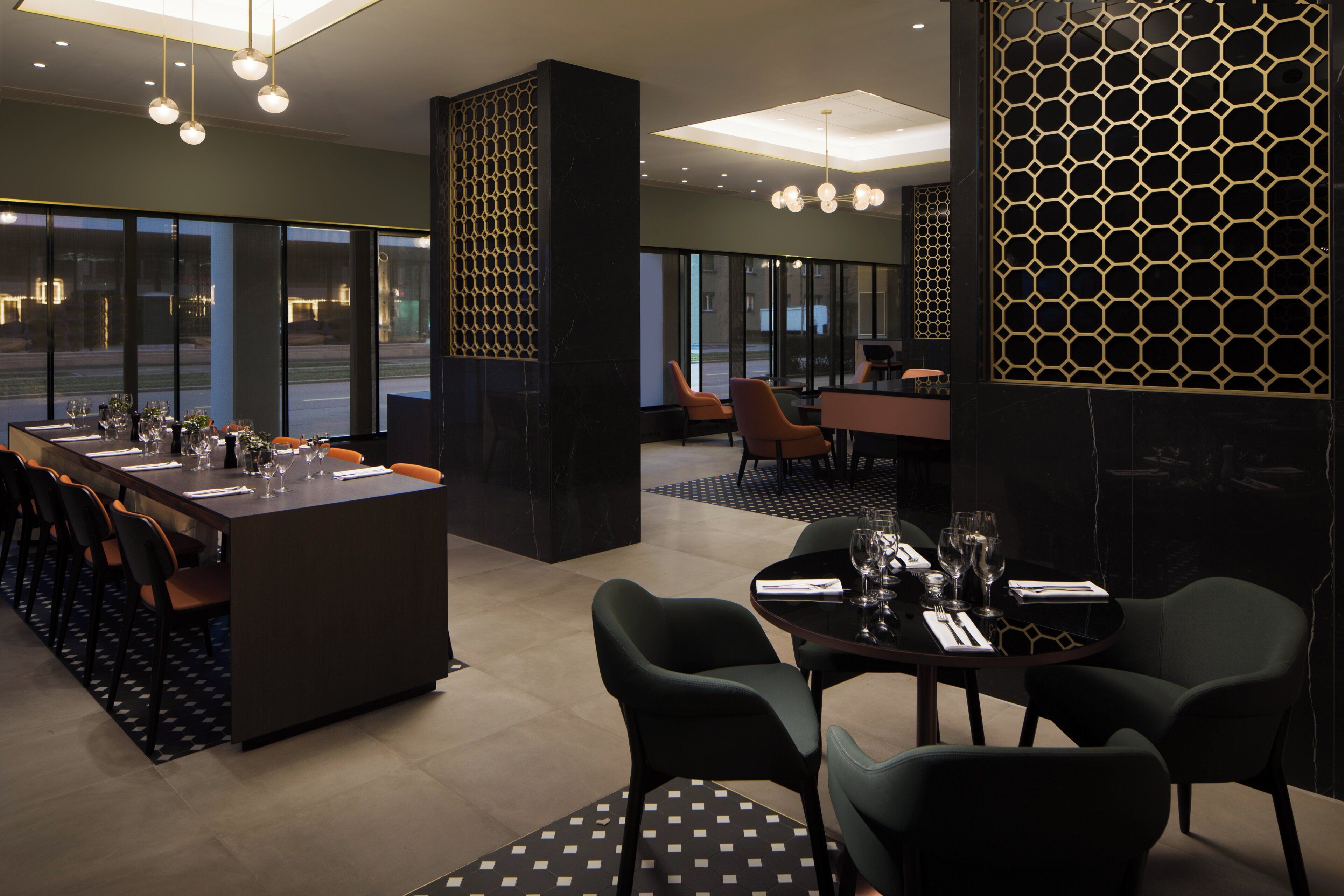 A modern dining area with a long table set for a meal, surrounded by chairs.