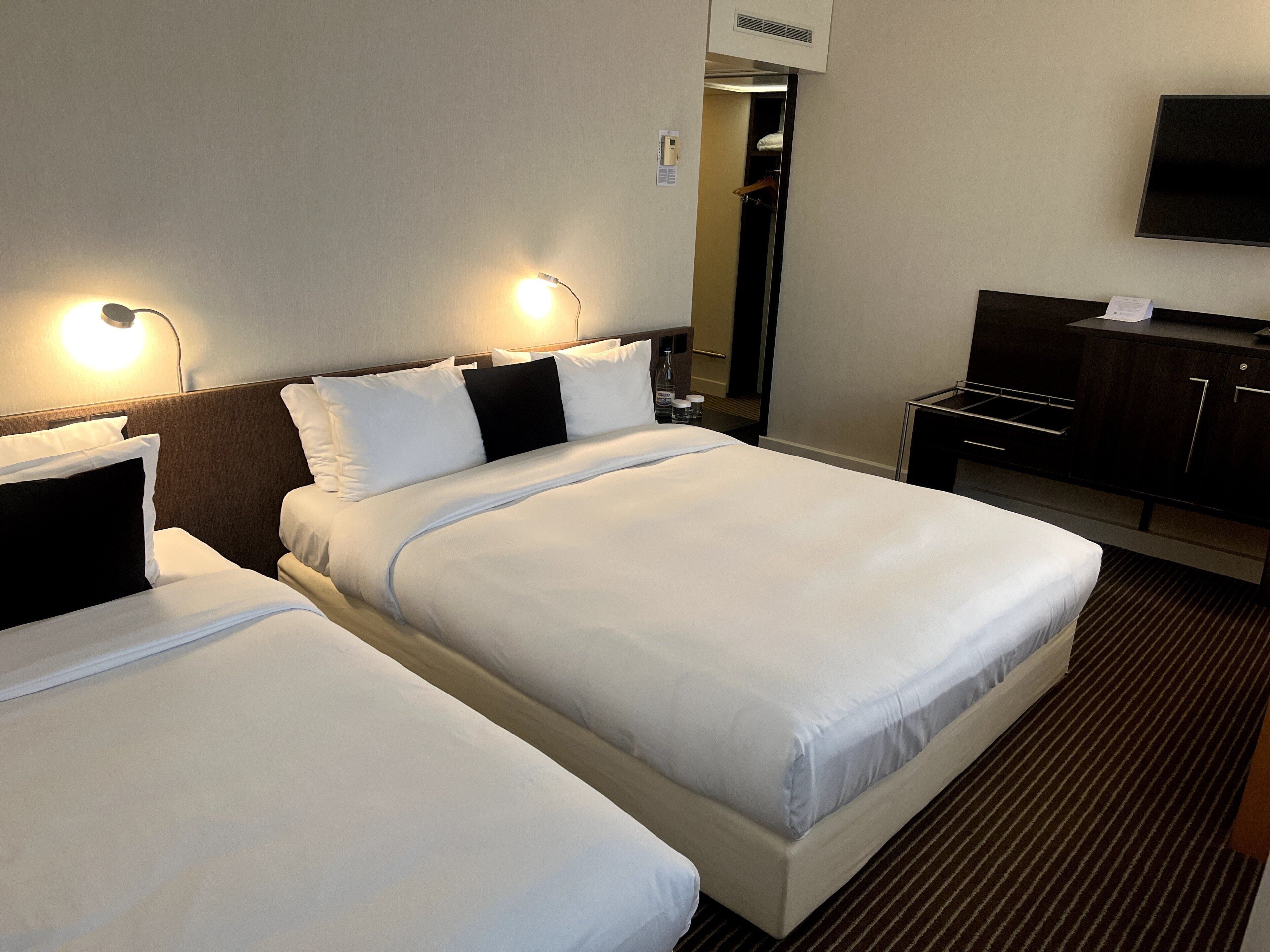 Ett hotellrum med två sängar, en TV, ett skrivbord och en garderob.