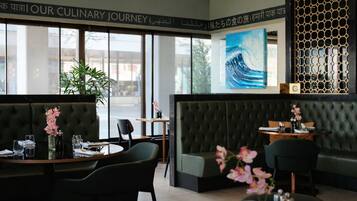 Un interior de restaurante con un amplio ventanal, un sofá y una mesa de comedor.