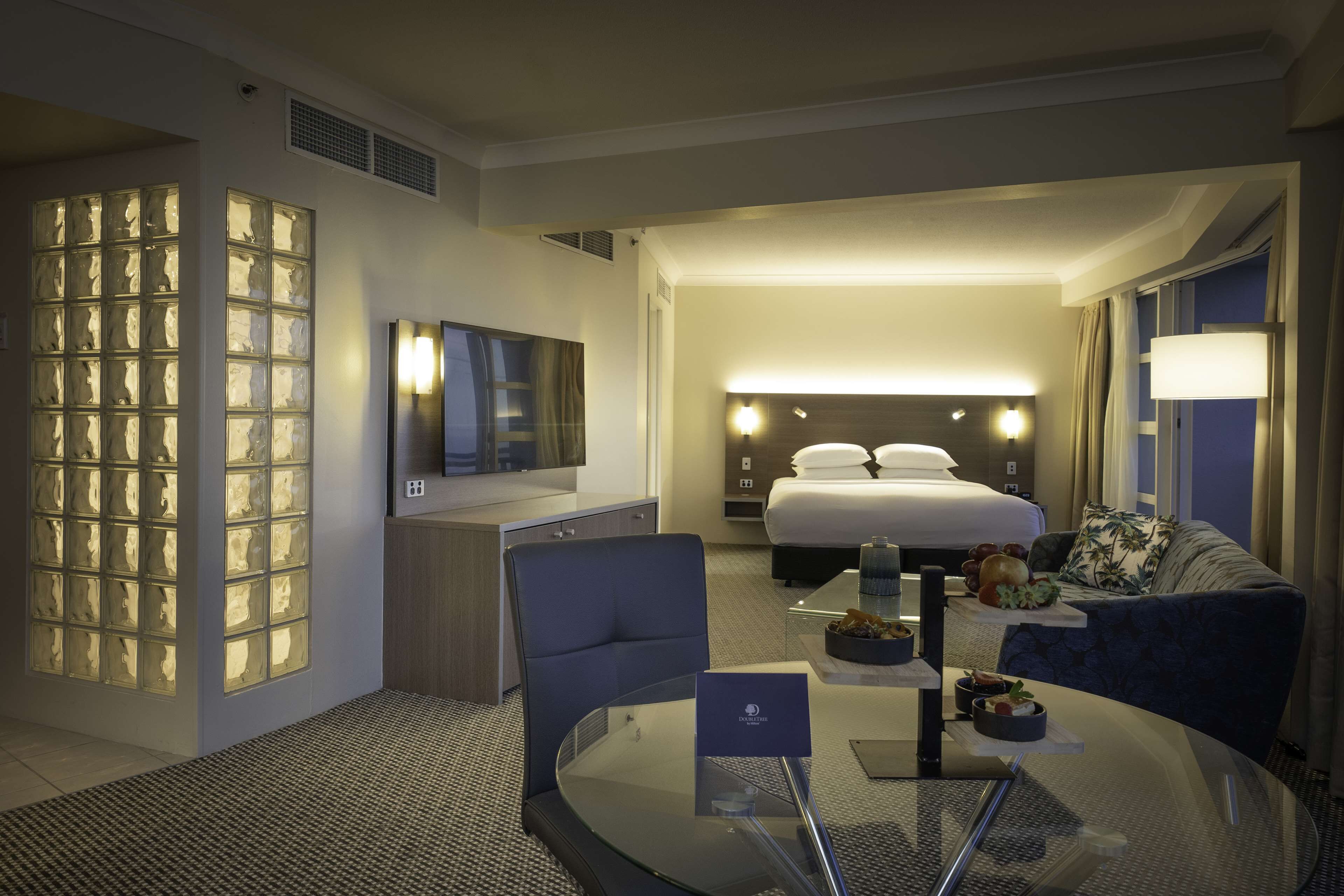 Une chambre d’hôtel équipée d’un lit, d’un bureau, d’une télévision et d’un coin salon avec une table et des chaises.