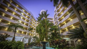 A multi-story hotel with balconies, a central fountain, and lush tropical landscaping. - DoubleTree by Hilton Hotel Cairns (Cairns)