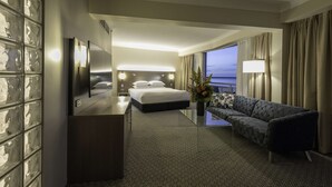 A hotel room with a bed, a sofa, a desk, and a large window with curtains. - DoubleTree by Hilton Hotel Cairns (Cairns)