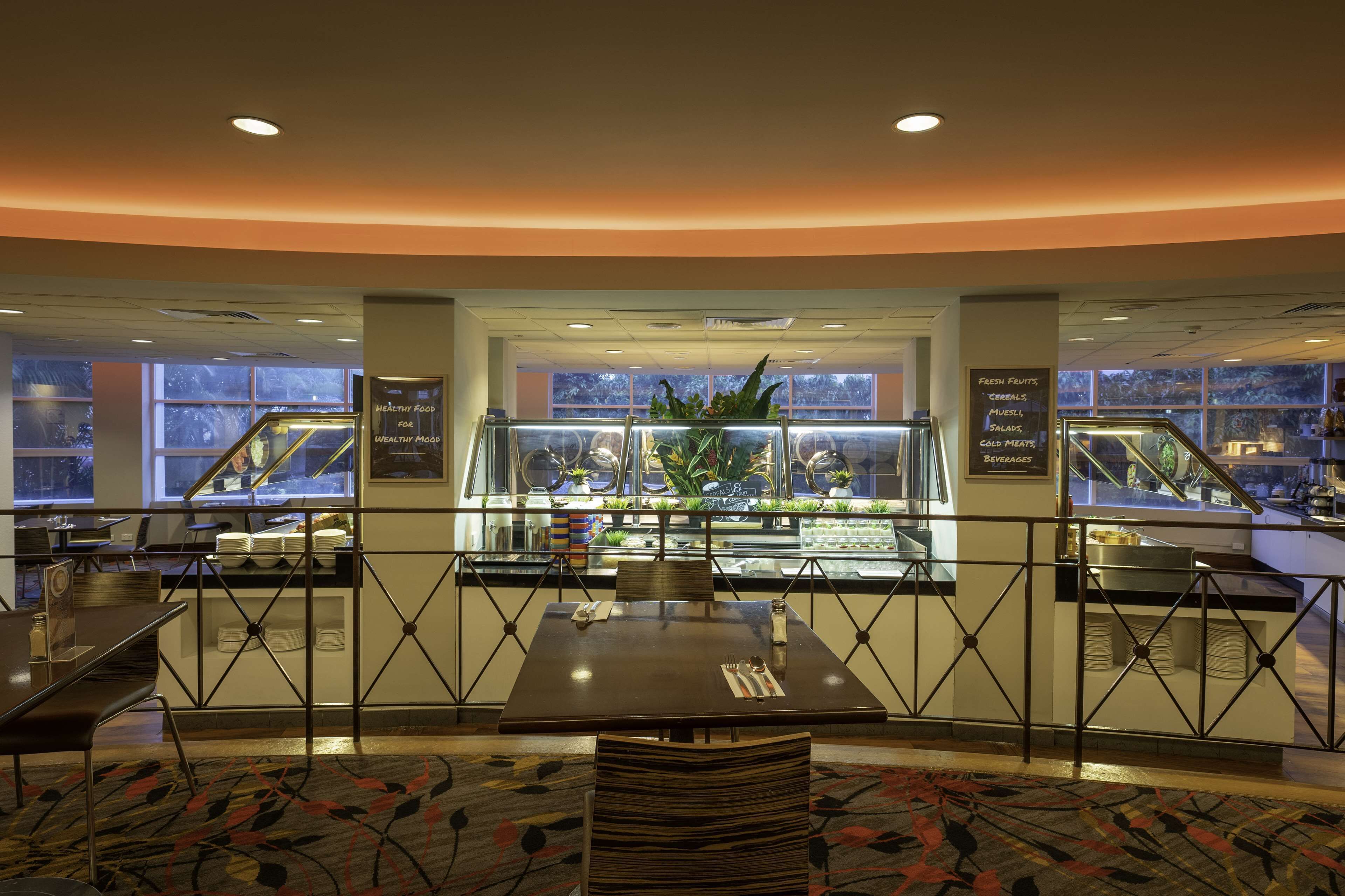 Un restaurant doté d’une cloison en verre, d’un espace buffet et d’un coin salon agrémenté d’un tapis à motifs.
