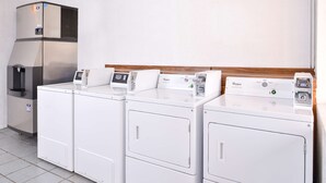 A row of white front-loading washers and dryers in a commercial setting. - Americas Best Value Inn Clute Lake Jackson (Clute)