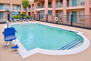 Una piscina con sillas azules, una silla de salvavidas y un flotador.