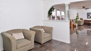 A lobby with two armchairs, a coffee table, a plant, and a view of the outside through a window. - Americas Best Value Inn Clute Lake Jackson (Clute)