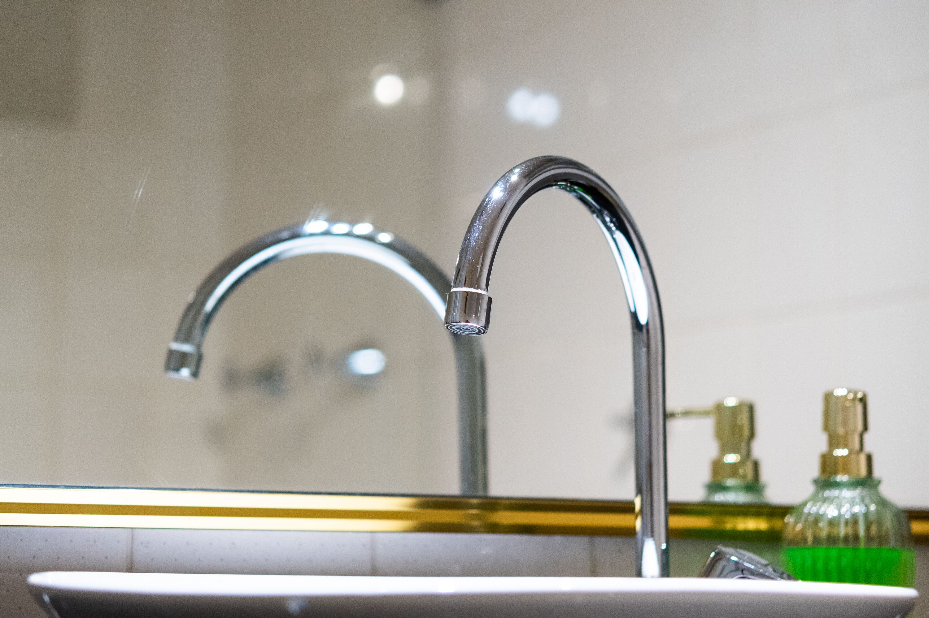 Et badeværelsesvask med en kromarmatur og et spejl over.