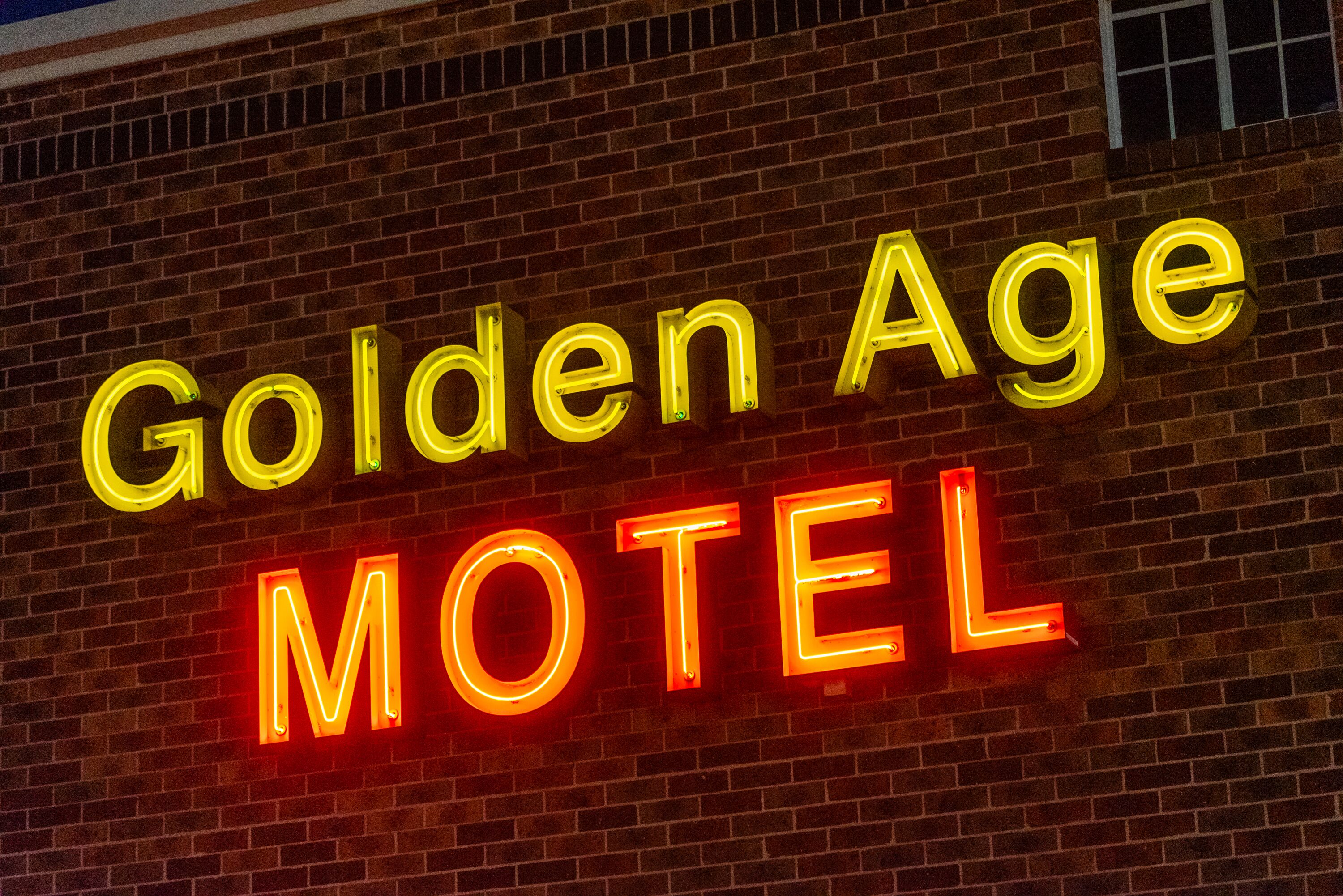 Un letrero de neón sobre una pared de ladrillo que dice "Golden Age Motel".