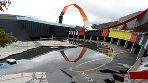 A modern building with a unique curved roof structure and a reflective water feature in front. - Golden Age Motor Inn Queanbeyan (Queanbeyan East)