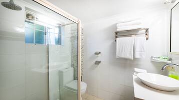 A modern bathroom with a glass-enclosed shower, a white toilet, a sink with a mirror, and a towel rack with two towels.