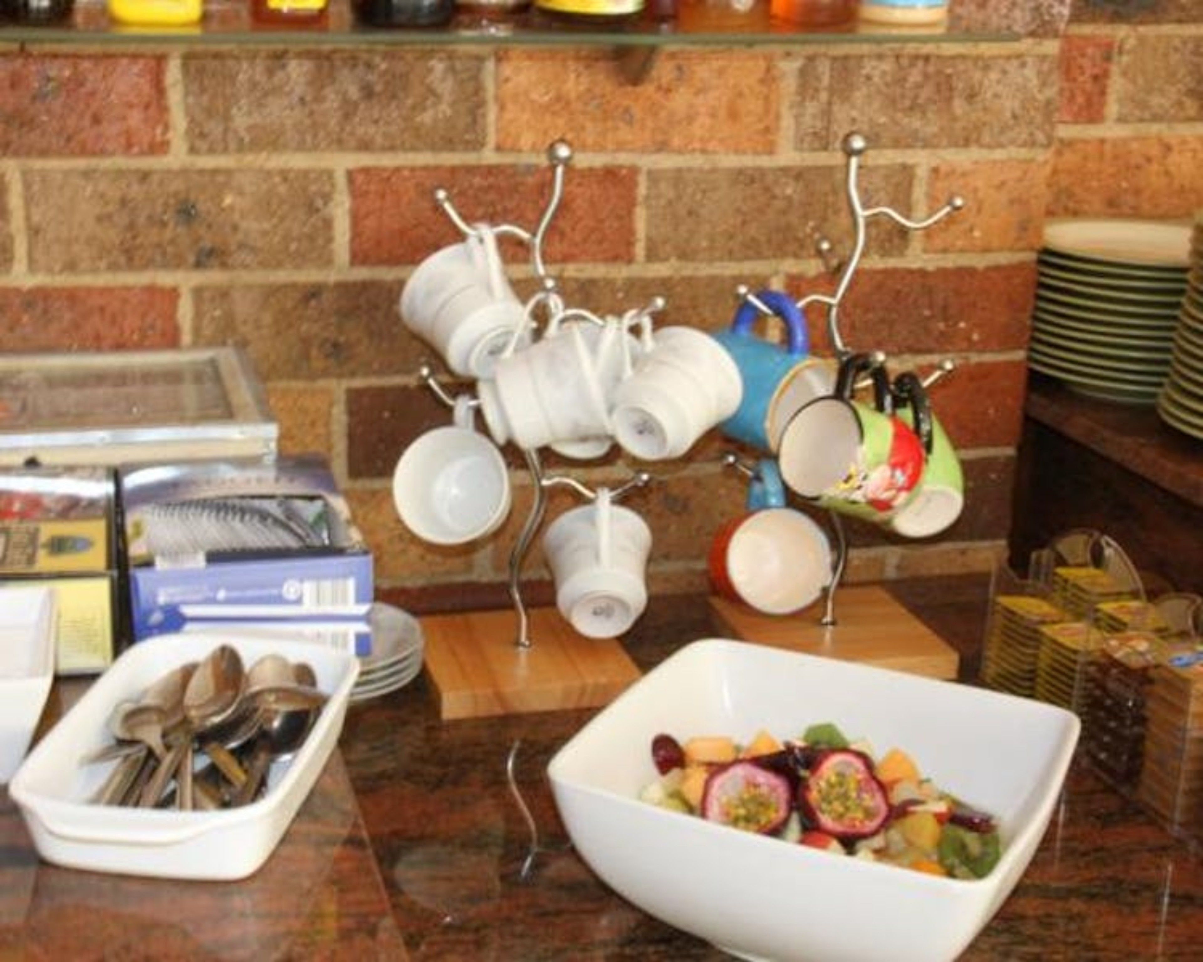 A kitchen counter with a fruit bowl, utensils, and a mug rack.