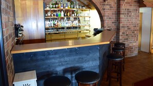 A bar area with a brick wall, wooden counter, and stools. - Golden Age Motor Inn Queanbeyan (Queanbeyan East)