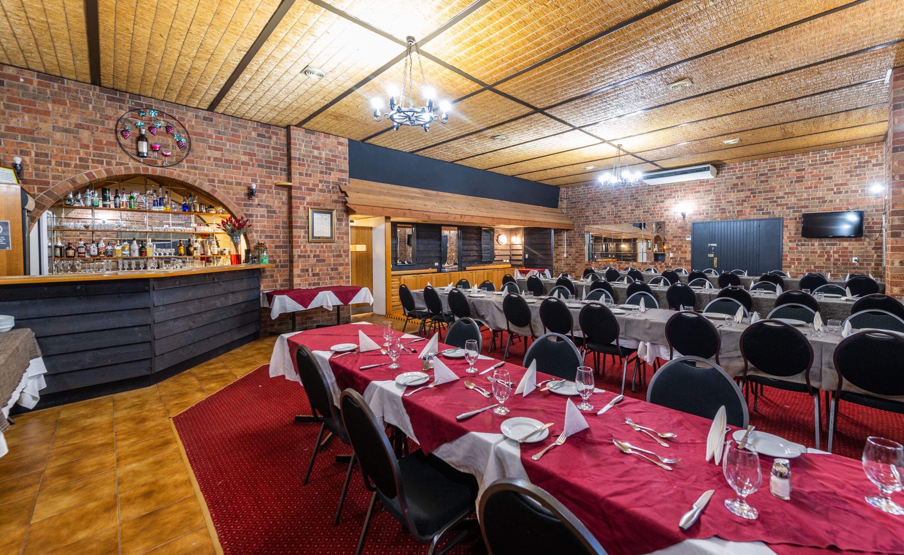 A restaurant with brick walls, a bar area, and multiple tables set for dining.