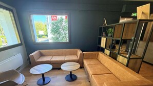 Un área de estar moderna con un sofá, dos mesas redondas y una estantería.