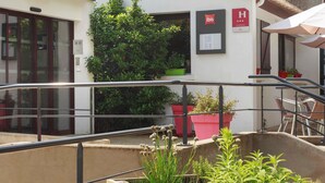 Un hotel Ibis con fachada moderna, zona de estar al aire libre y plantas en macetas.