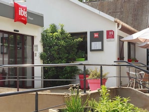 An ibis hotel with a modern facade, outdoor seating area, and potted plants. - ibis Dieppe Val Druel (Dieppe)