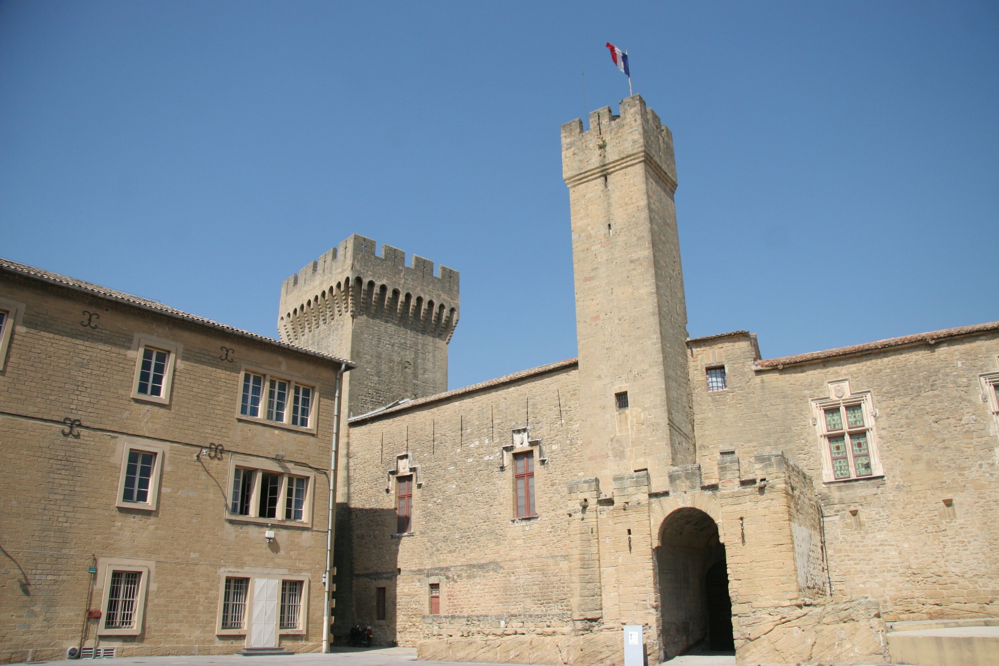 A historic stone building with a tall tower and a smaller fort-like structure.